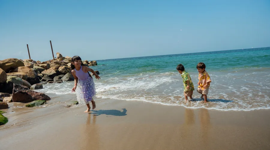 A mother and children playing together at the water’s edge
