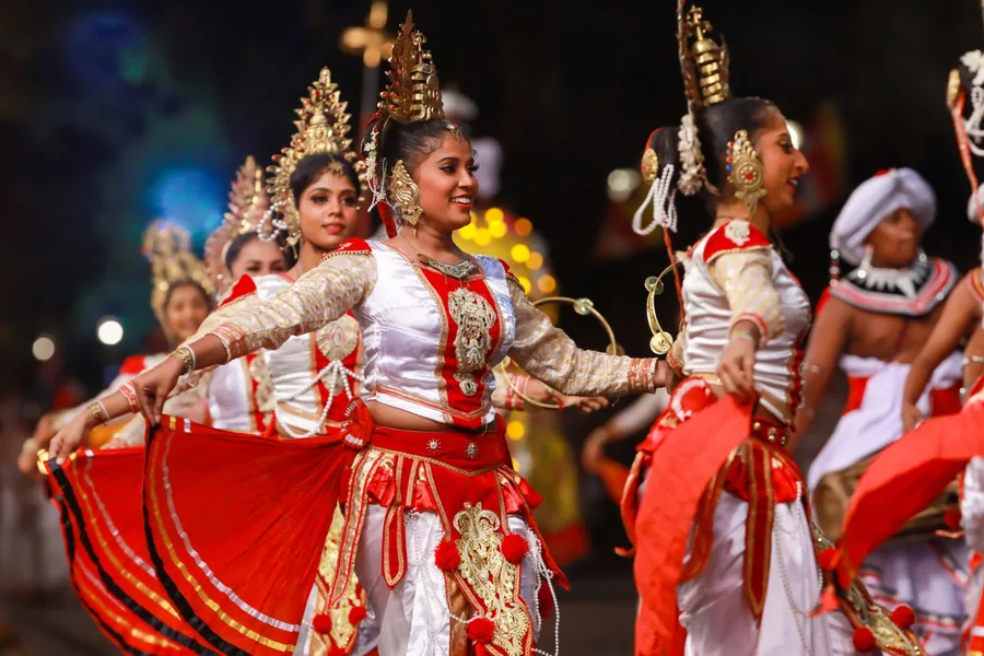 Dancers in red and gold costume performing at a night-time perahera
